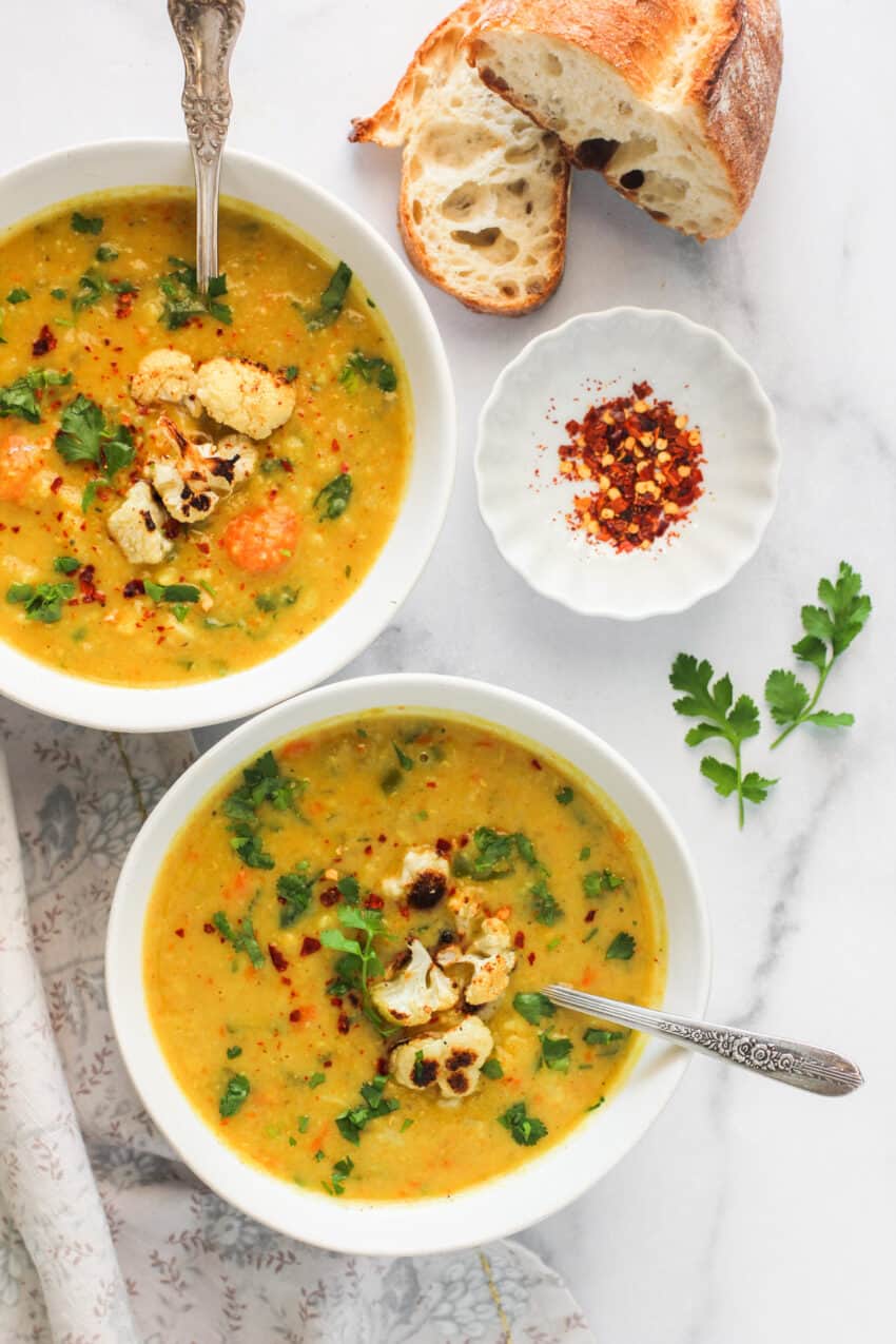 mulligatawny soup served in 2 bowls with bread on the side 