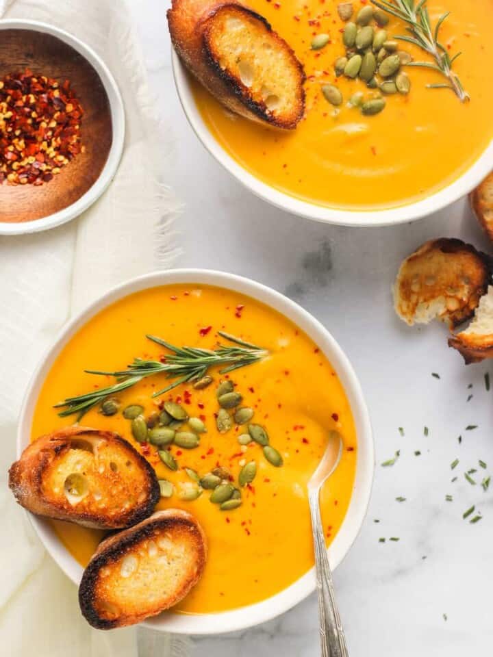 butternut squash soup served in 2 white bowls