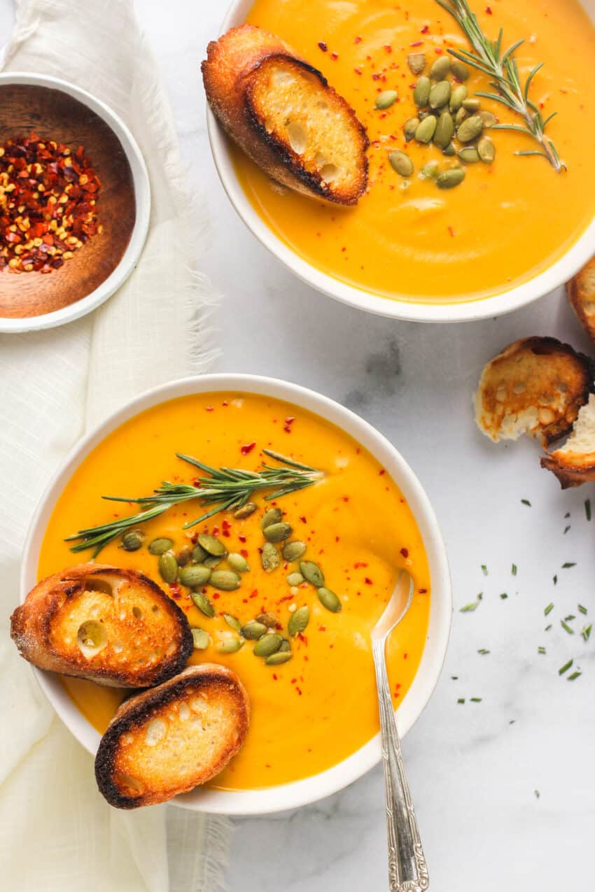 Butternut squash soup served in 2 white bowls 