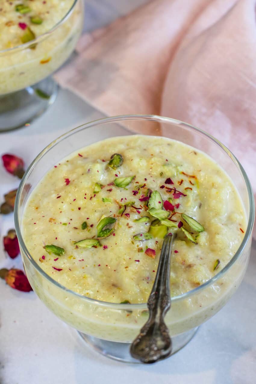 rice kheer in a glass bowl garnishes with pistachios and dried rose petals