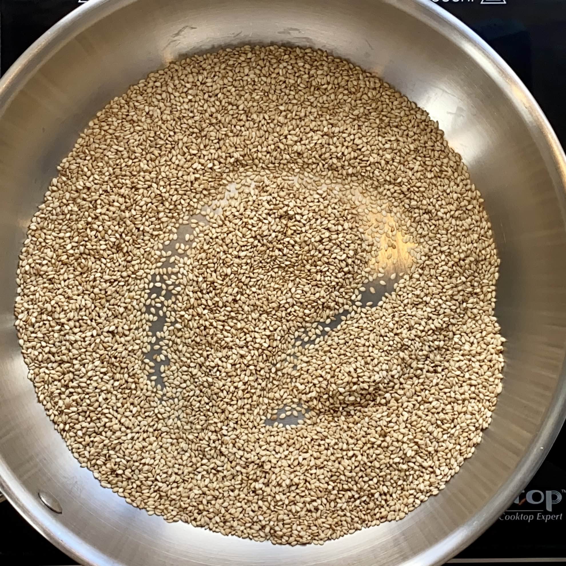 roasting sesame seeds in a stainless steel pan.