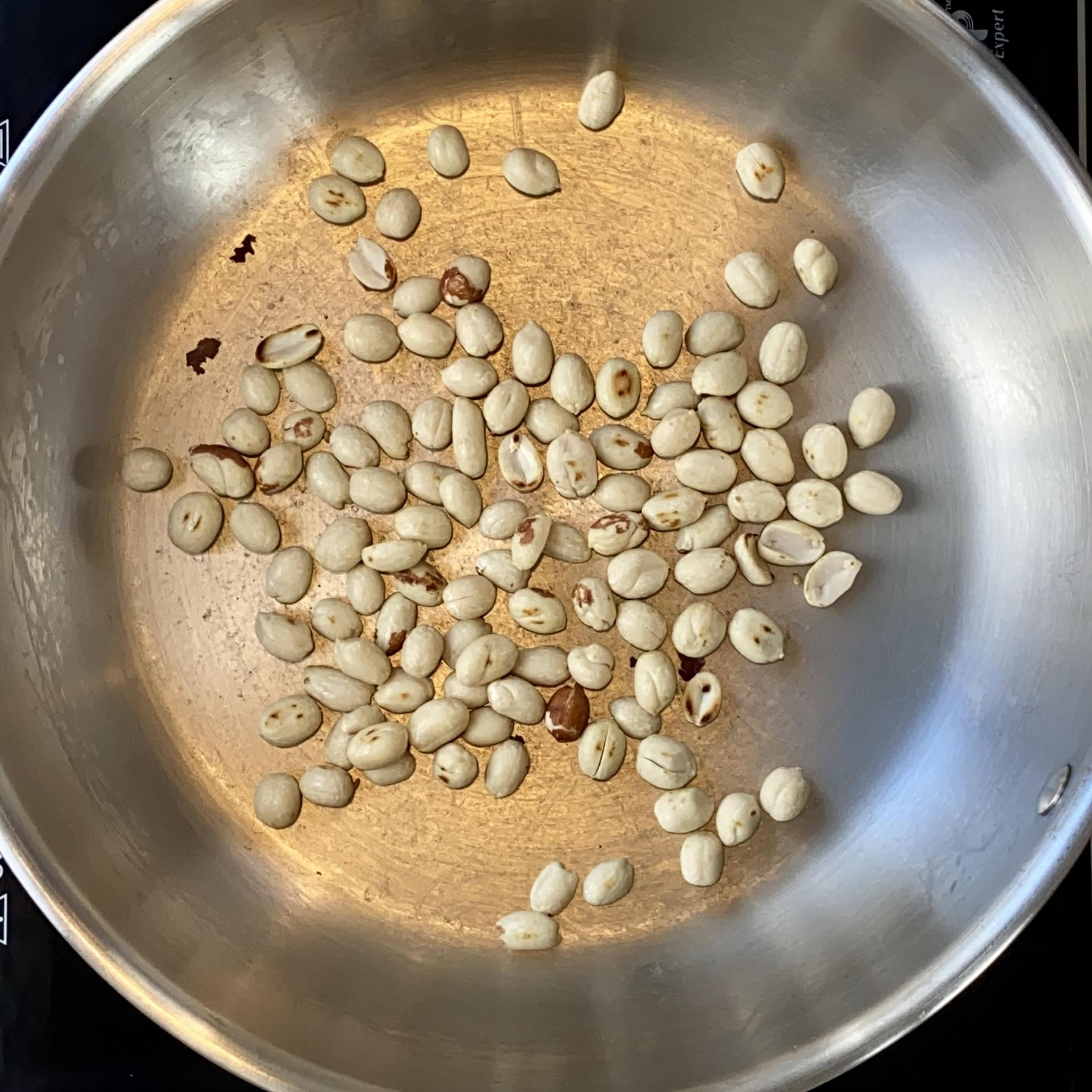 roasting peanuts in a stainless steel pan.