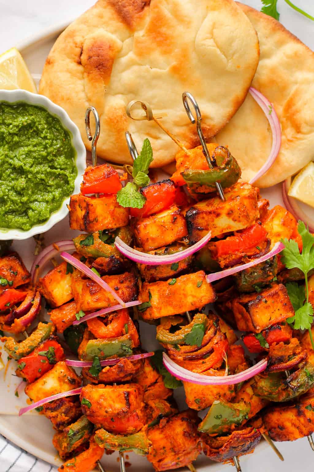 Air fryer paneer tikka bites charred and golden on skewers for Indian Pakistani party appetizer with mint chutney