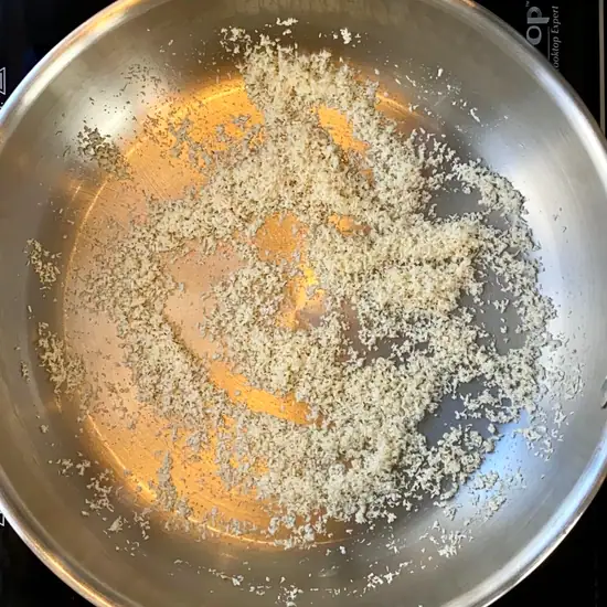 roasting dessicated coconut in a stainless steel pan.