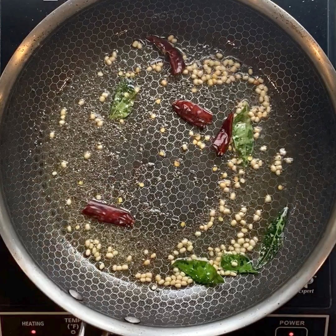 non stick pan with urad dal, mustard seeds, curry leaves and dried red chili tempering.