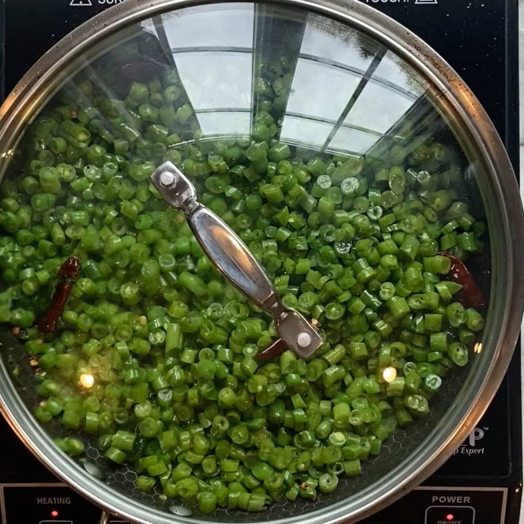 green beans poriyal in a pan covered with glass lid.