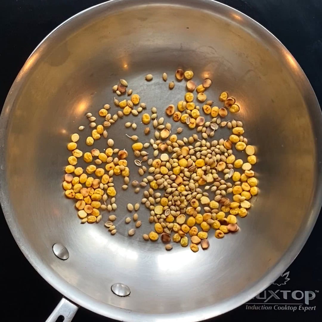 roasting lentils and coriander seeds in a stainless steel pan.