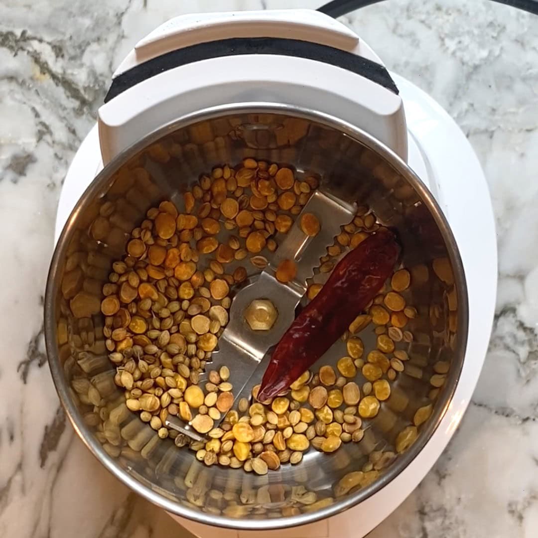 roasted coriander seeds, lentils and dry red chili in a grinder jar.