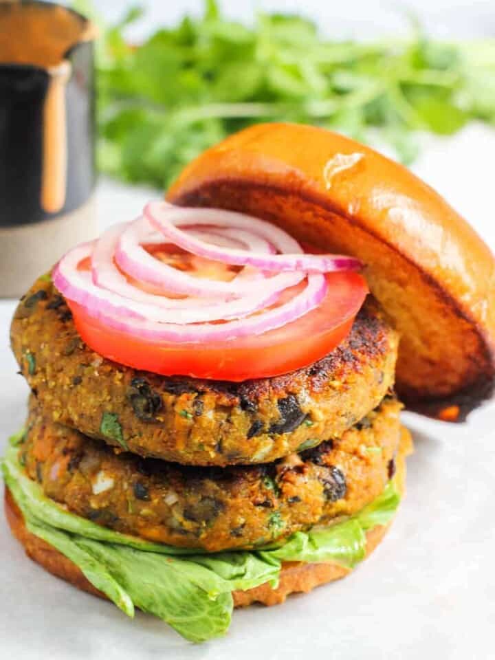 stacked burger patties on buns with lettuce, tomato and onion