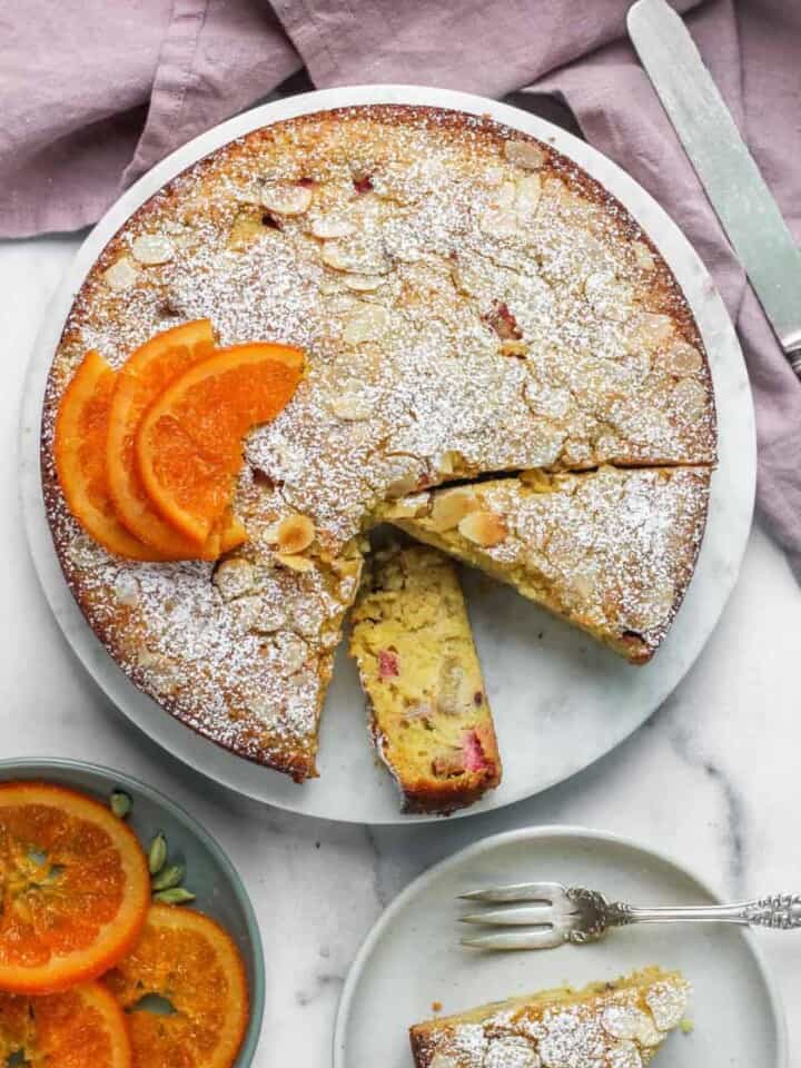 rhubarb almond cake with powdered sugar and candied orange slices