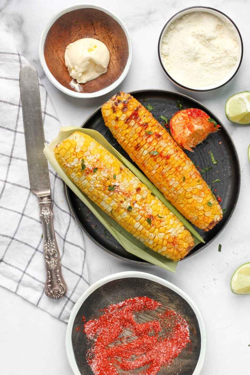 corn rubbed with salt, chili lime wedges with butter and cheese on the side 