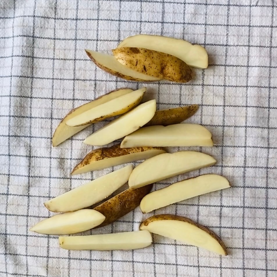 Raw potato wedges arranged on a white and gray checkered cloth.