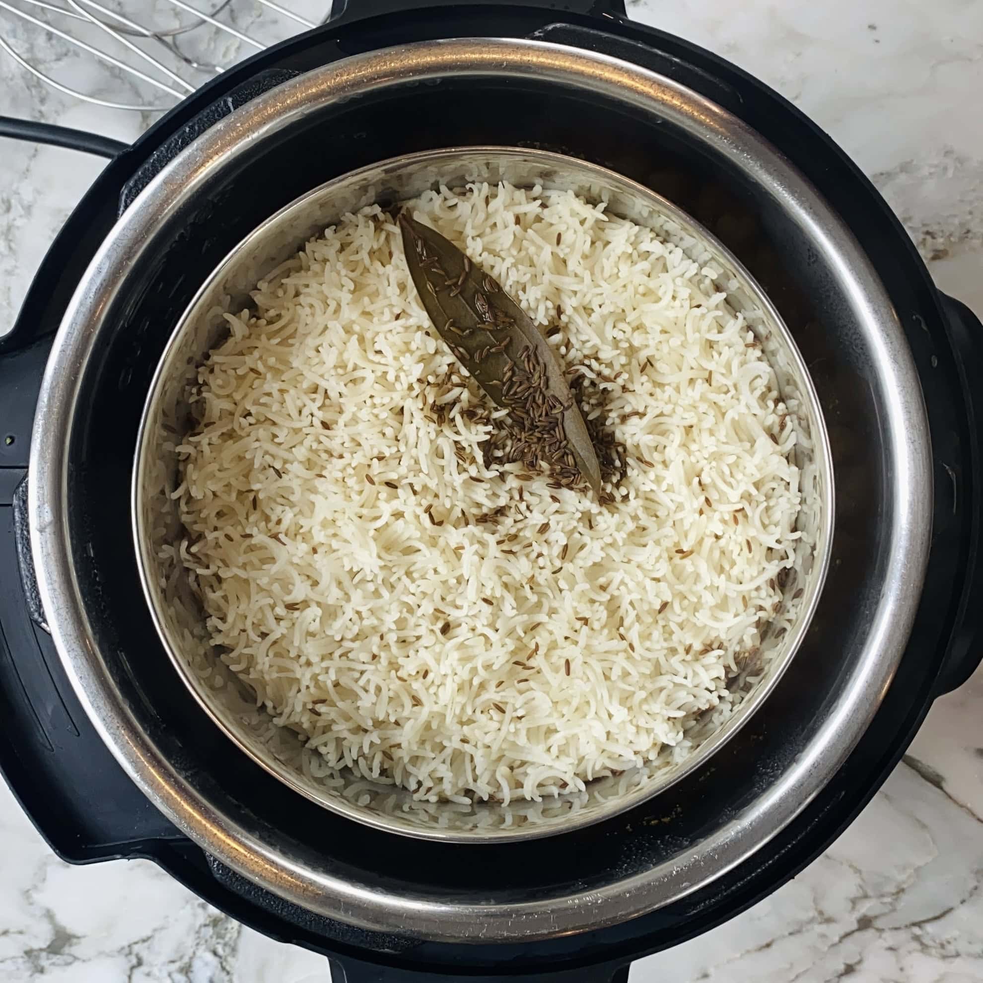 Cooked basmati rice with cumin seeds and a bay leaf in an Instant Pot