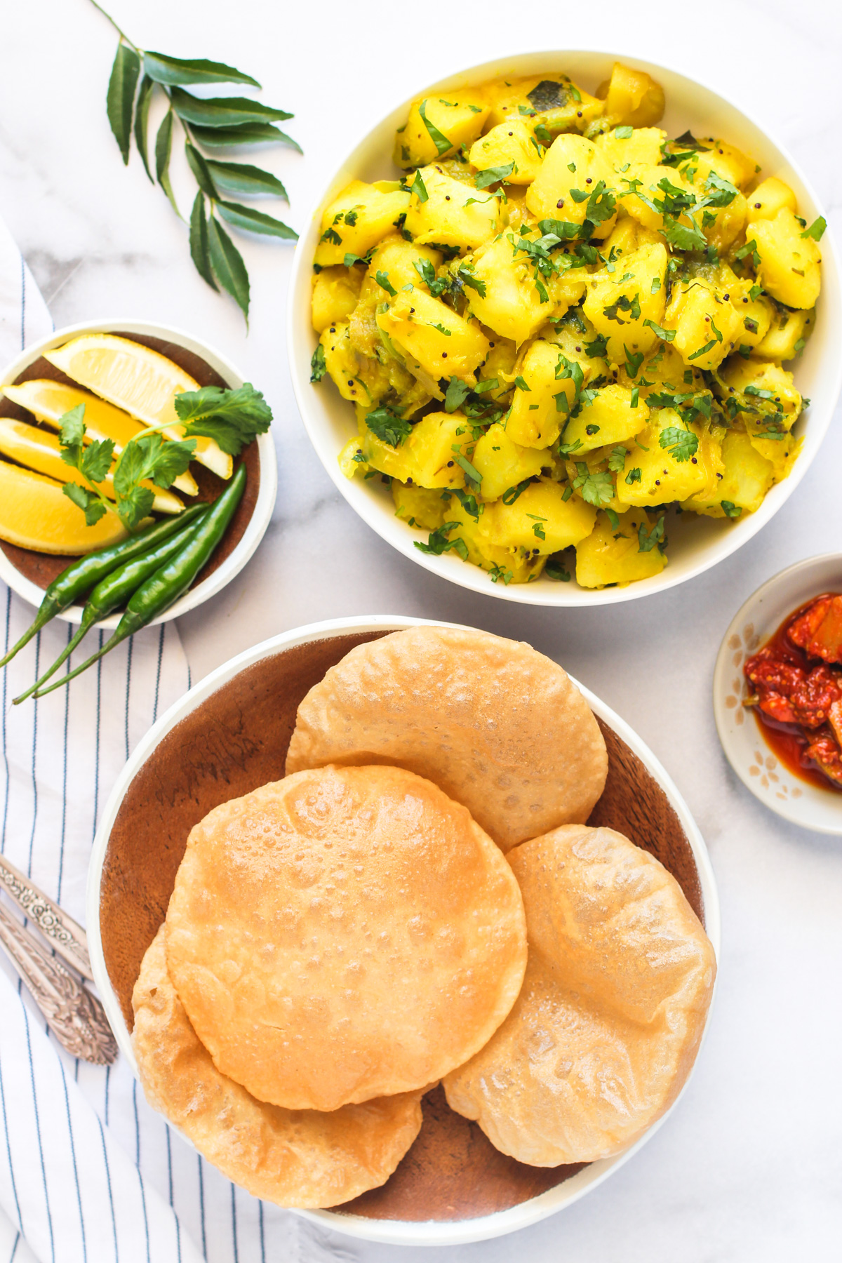 batata bhaji served in a a white bowl with puri and pickle 