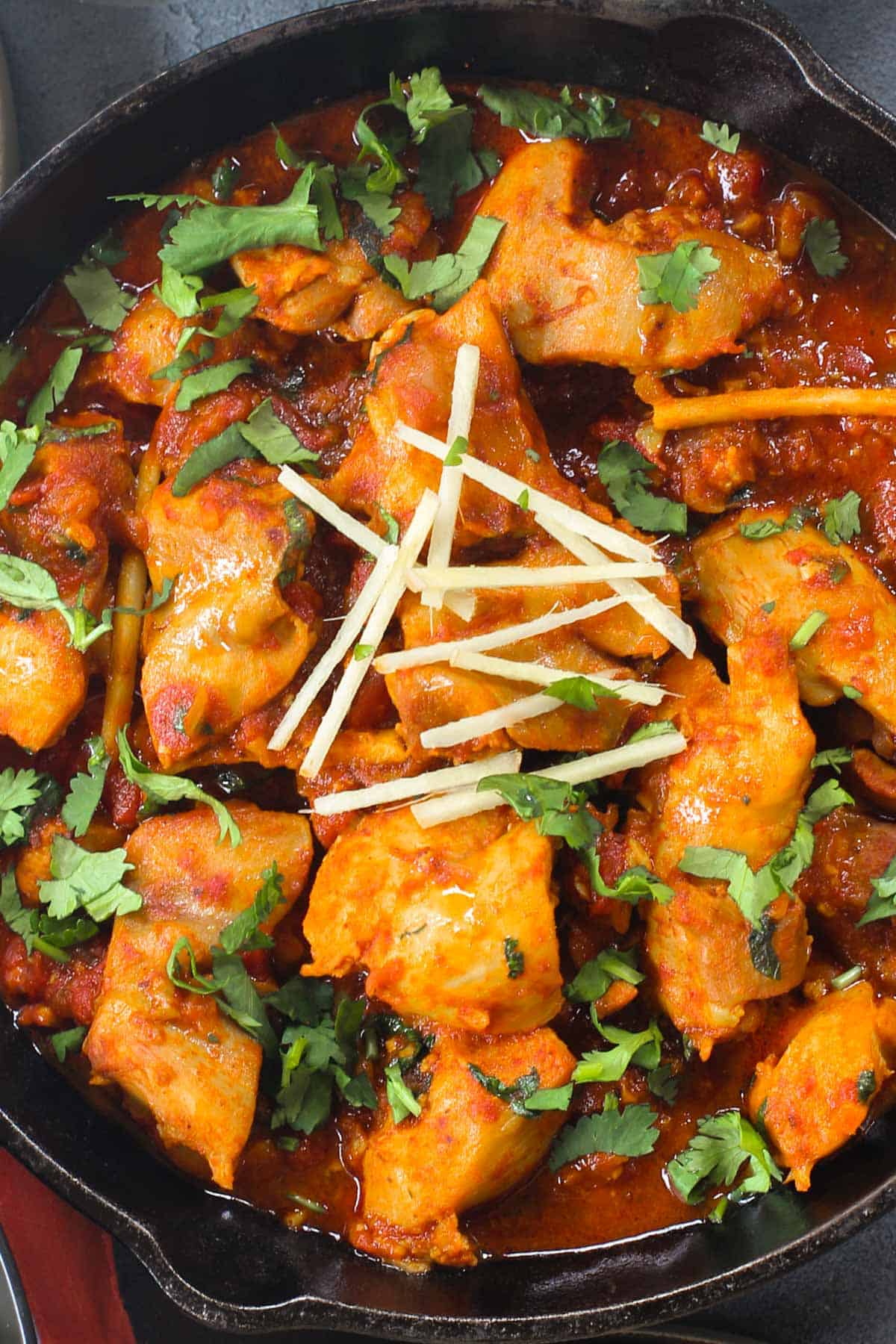 chicken karahi garnished with cilantro and julienned ginger  