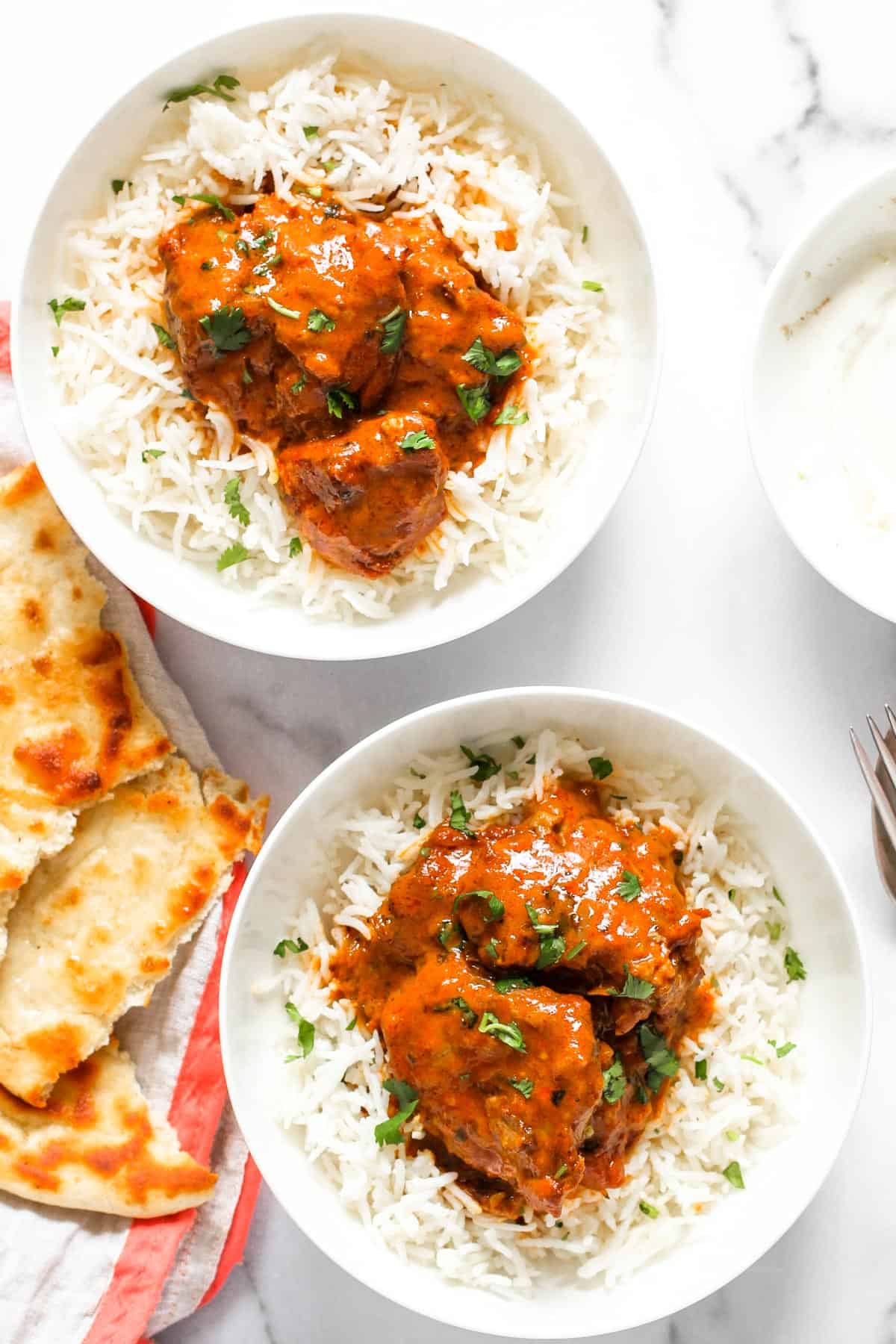 Butter Chicken Served on rice in 2 bowls and naan on the side 