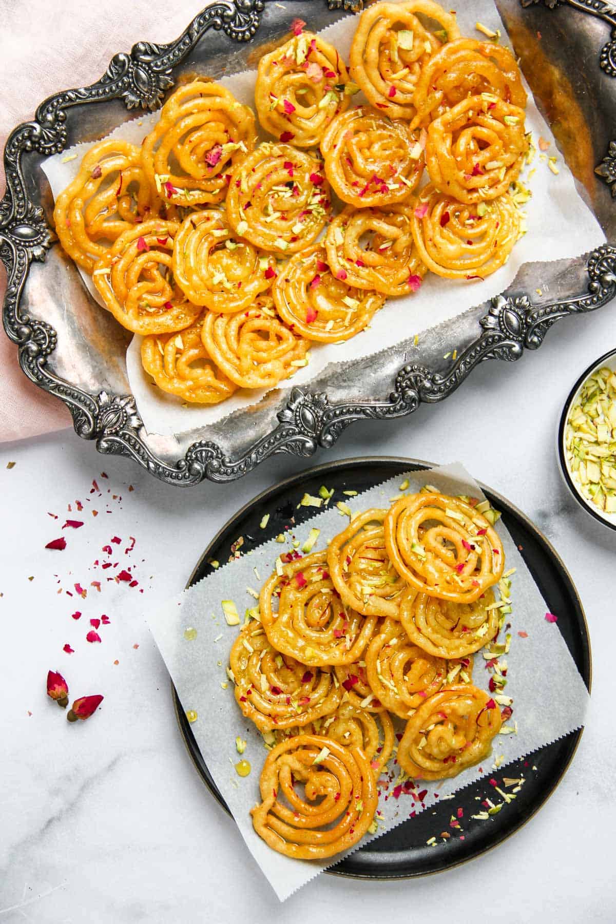 Jalebi served on a silver platter and a black plate 