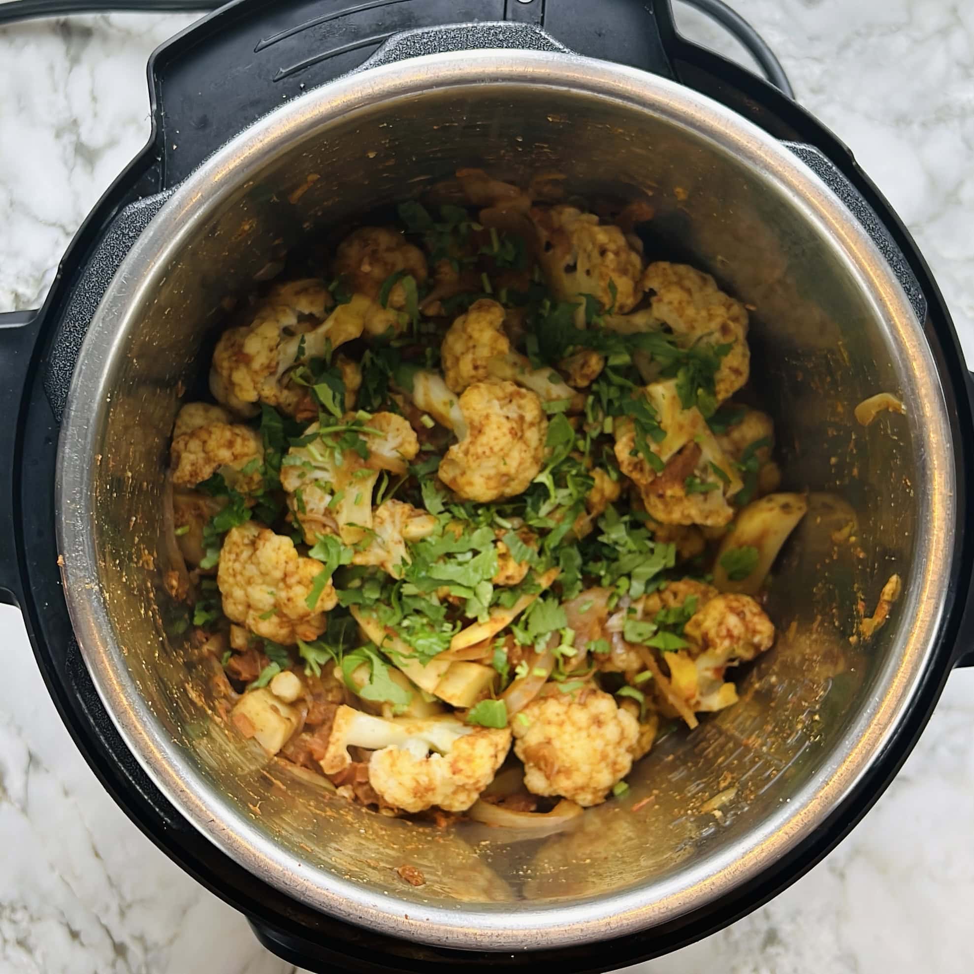 cooked aloo gobi in the Instant Pot garnished with cilantro.