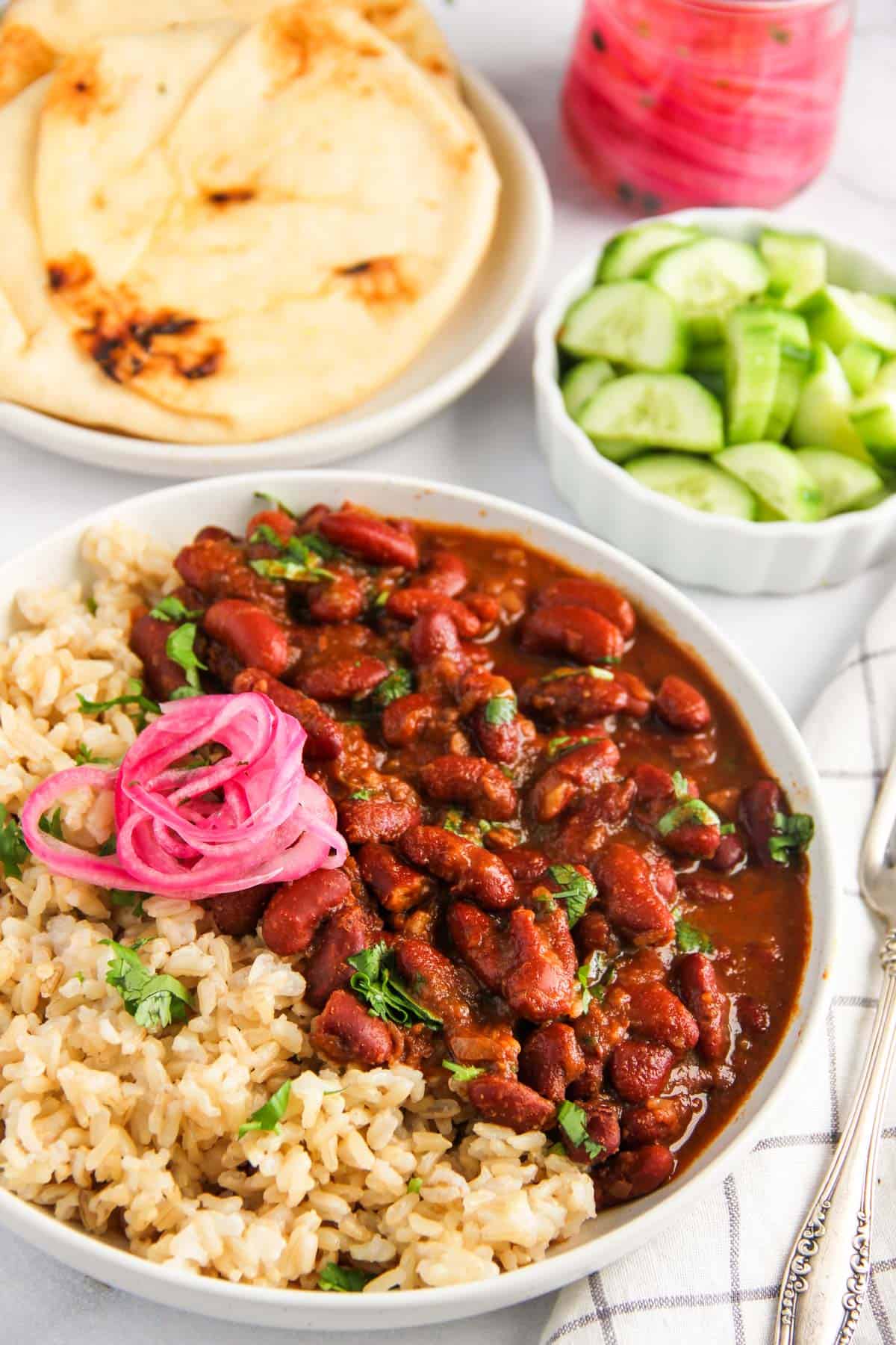 Rajma served with brown rice and pickled onions in a white bowl 