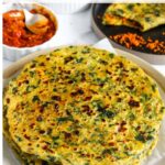 Stack of kale aloo paratha (whole wheat Indian flatbread with kale and potato) on a plate, with chutney and another paratha in the background.