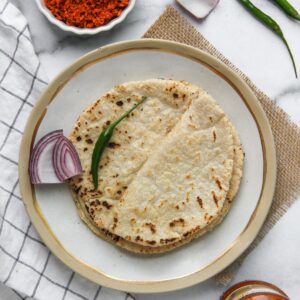 Jowar Rotis in a plate with onion and green chilli