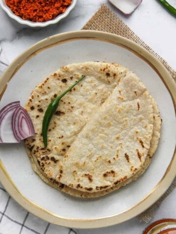 Jowar Rotis in a plate with onion and green chilli