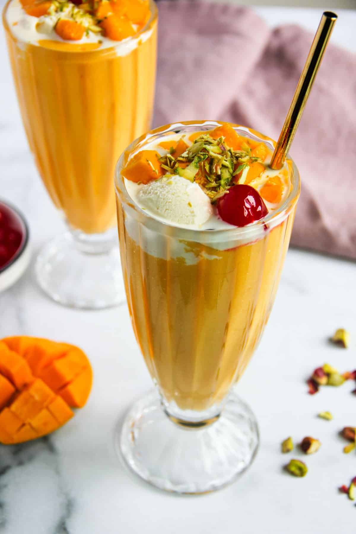 Mango Mastani served in a tall glass garnished with nuts and cherry 