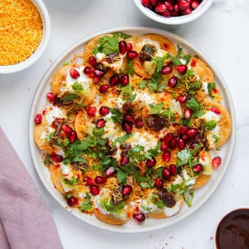 papdi chaat garnished with sev, cilantro and pomegranate seeds