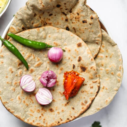 Bajra roti served with onion, green chili and Indian pickles