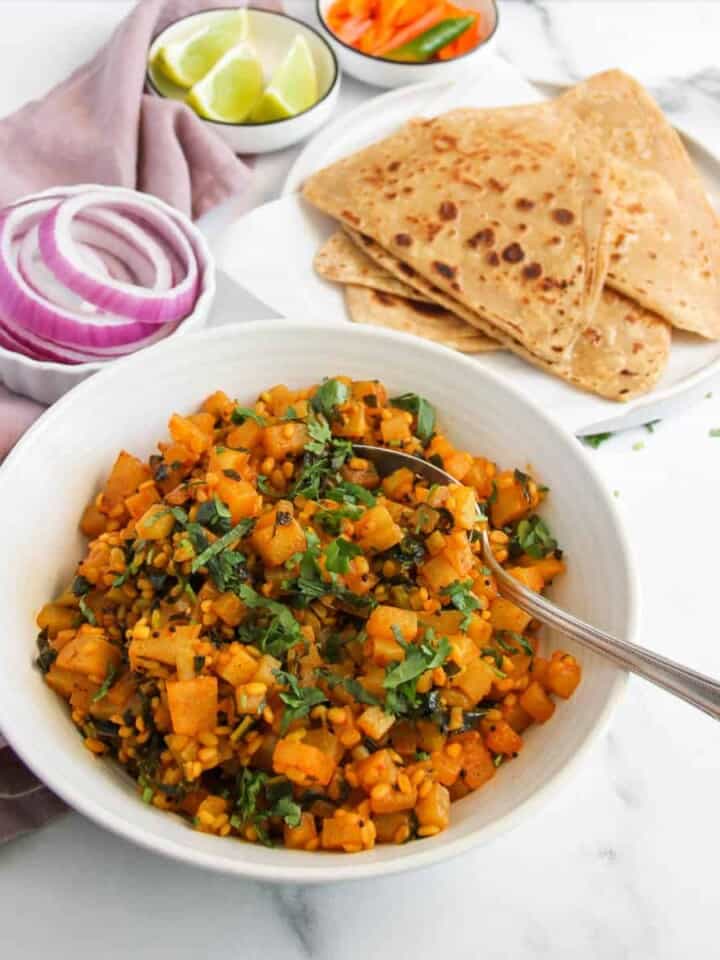 Kohlrabi curry served with parathas, lime wedges and onions