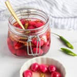 pickled pearl onions in a glass jar and a small white dish