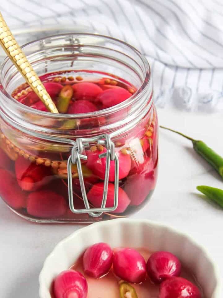 pickled pearl onions in a glass jar and a small white dish
