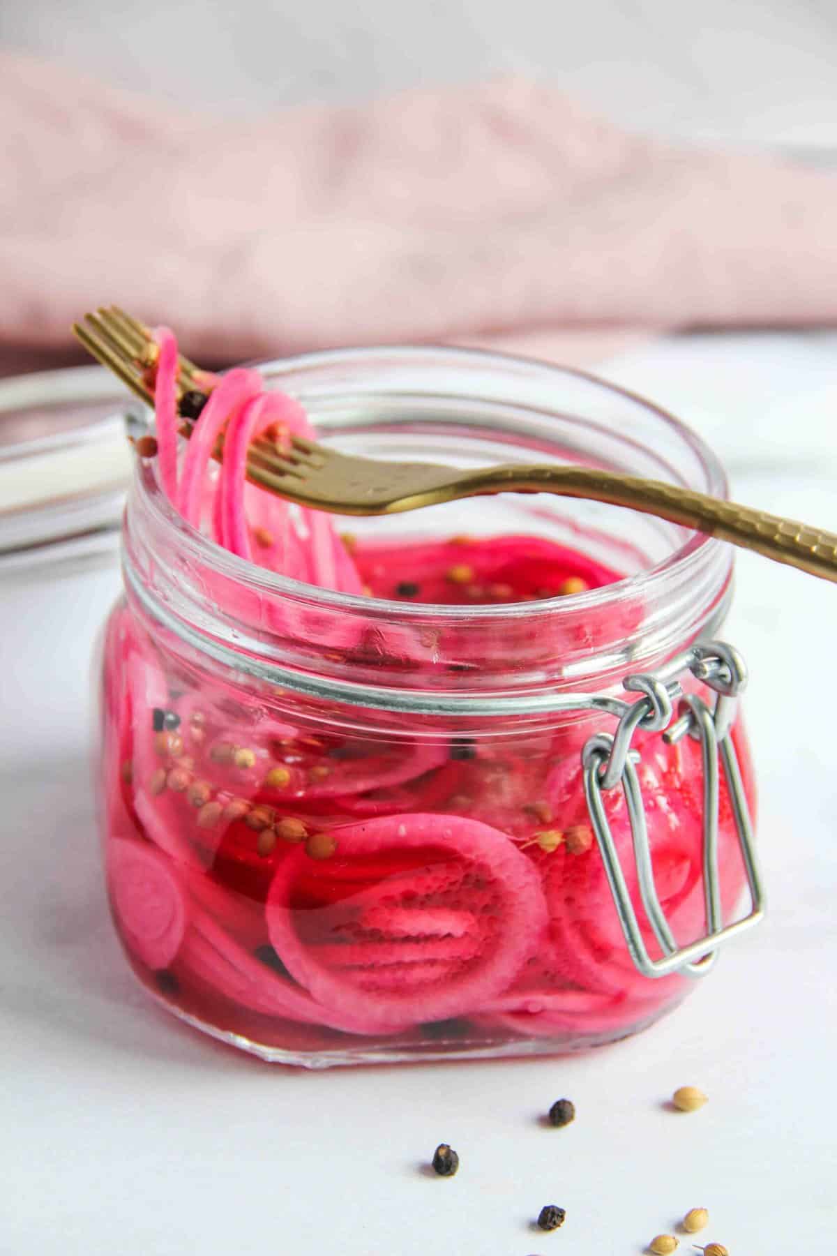 pickled onions in a jar with a fork on top 