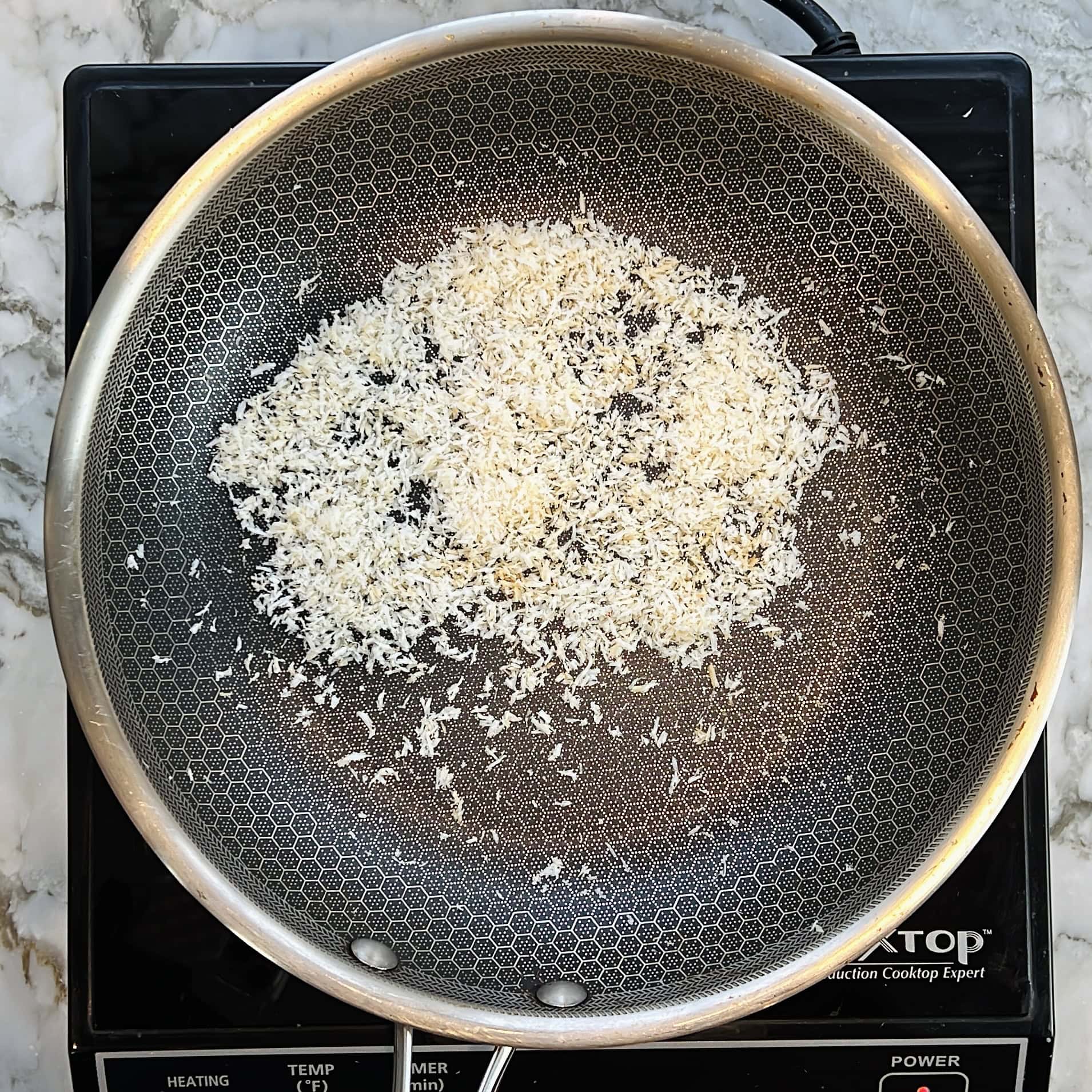 Roasting desiccated coconut in a pan.