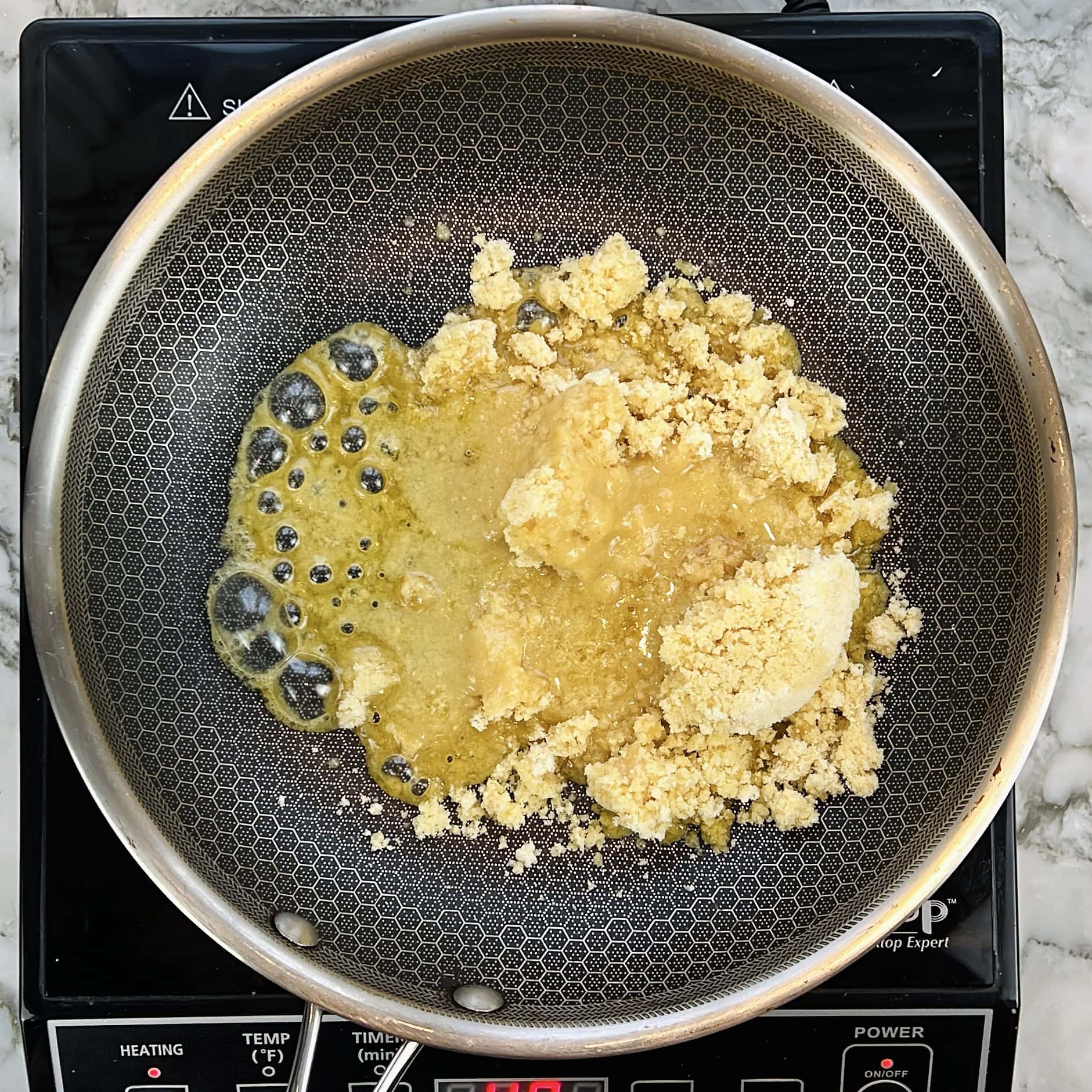 Melting jaggery in a nonstick pan.