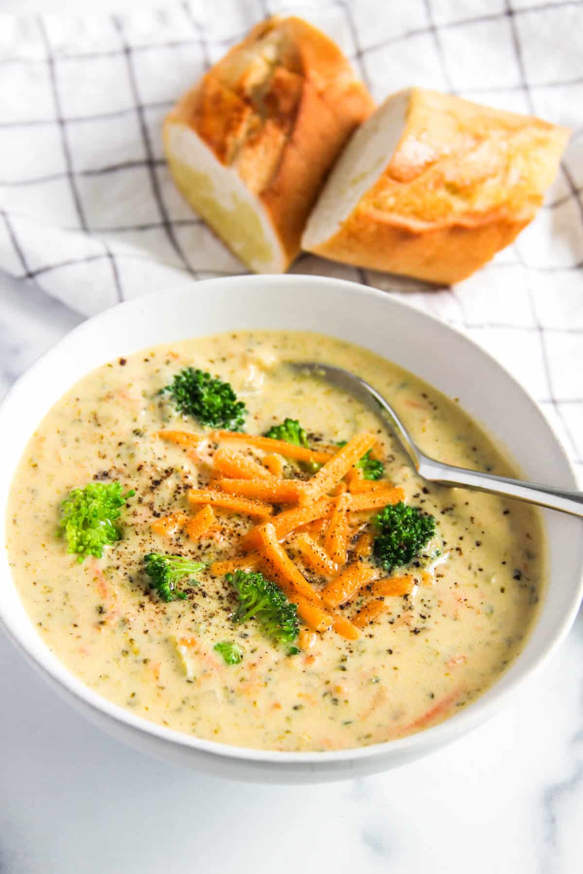 Broccoli cheddar soup served in a bowl topped with cheddar cheese and black pepper 