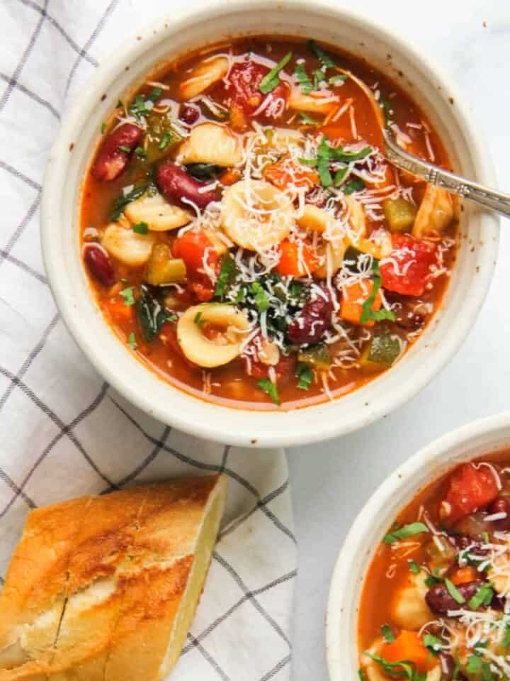 minestrone soup served in two white bowls