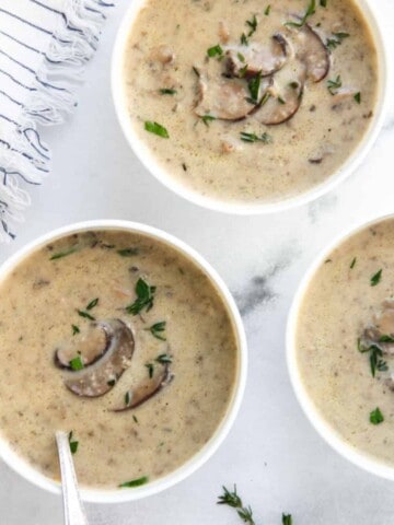 mushroom soup served in three white bowls