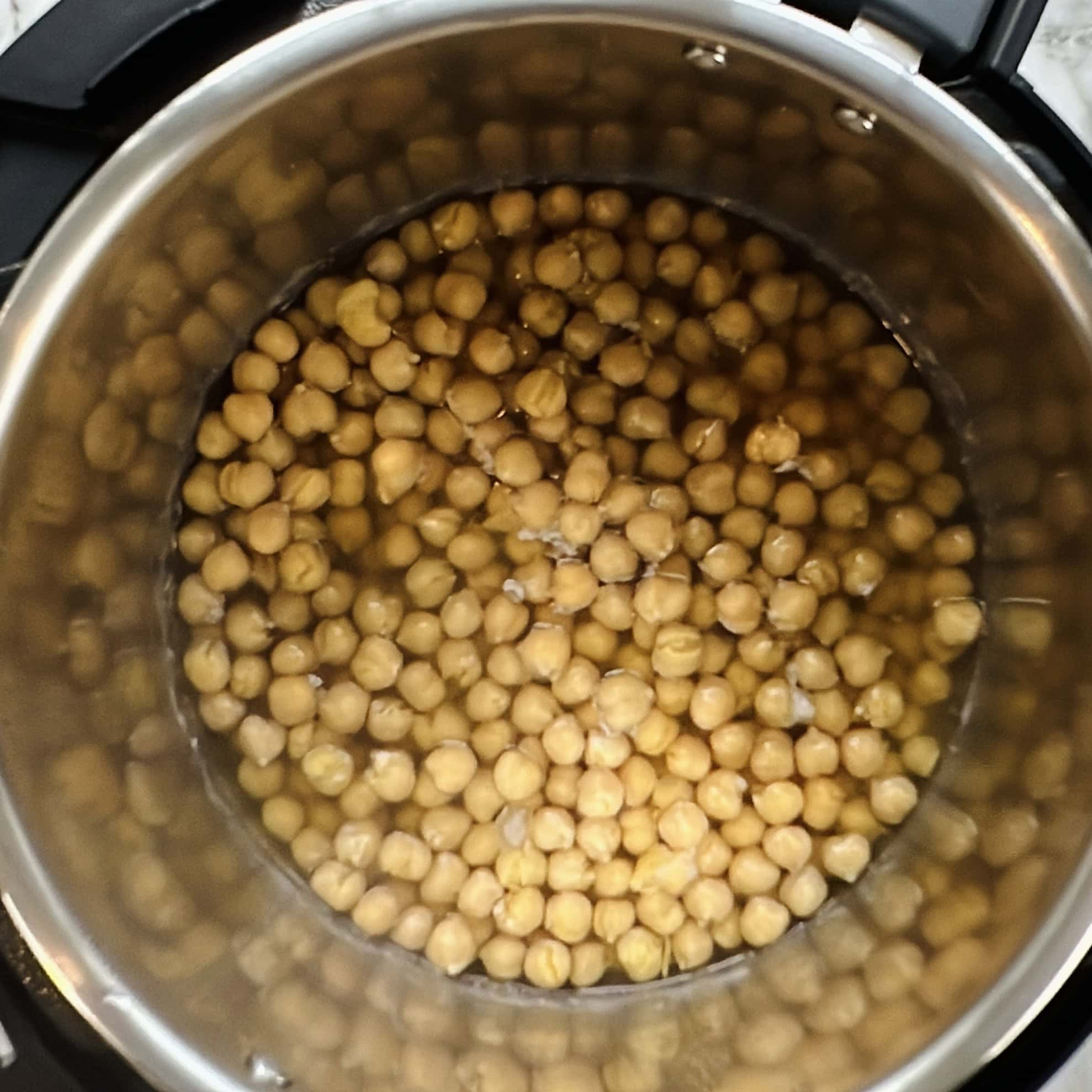 A pot filled with water and uncooked chickpeas, ready to be cooked.