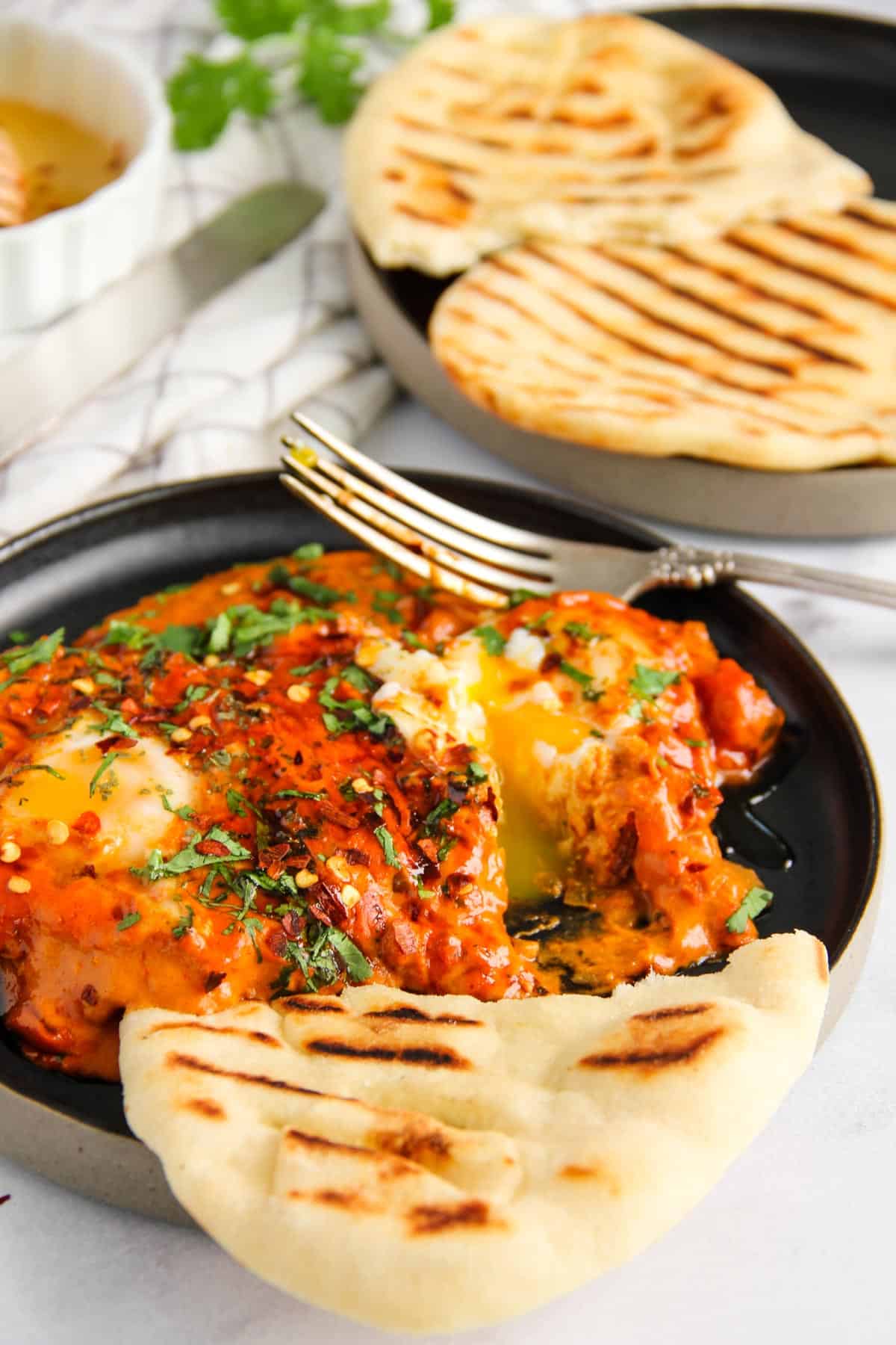 makhani shakshuka served in a black plate with naan