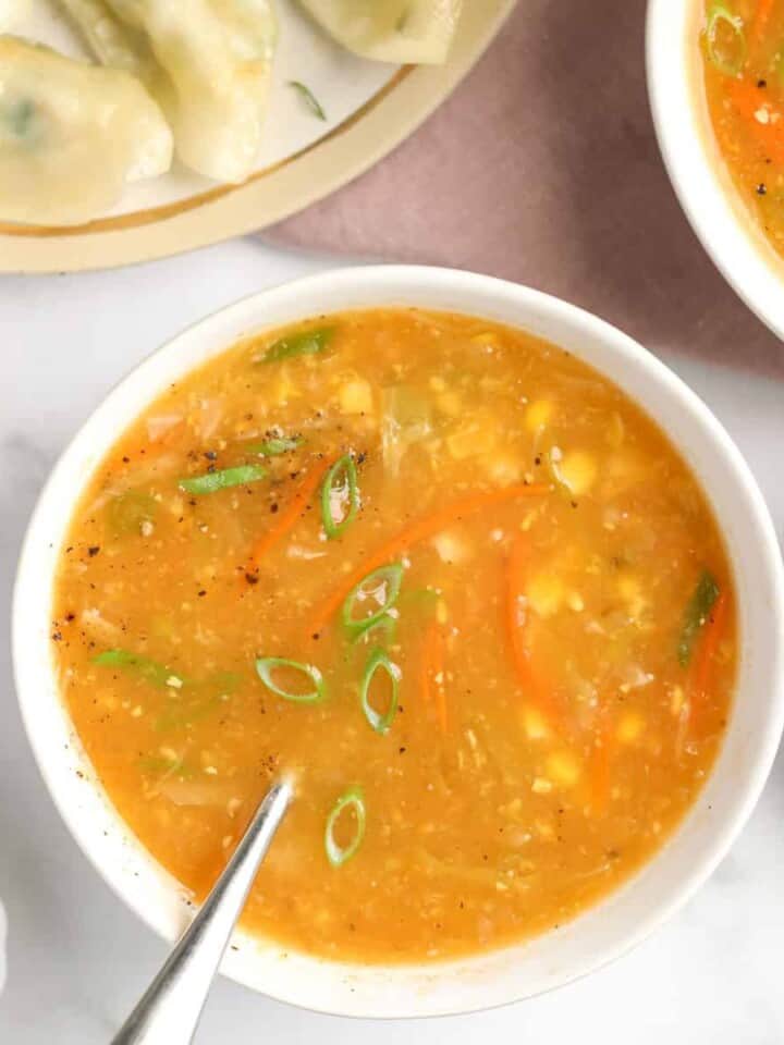 sweet corn soup in a white bowl garnished with scallions