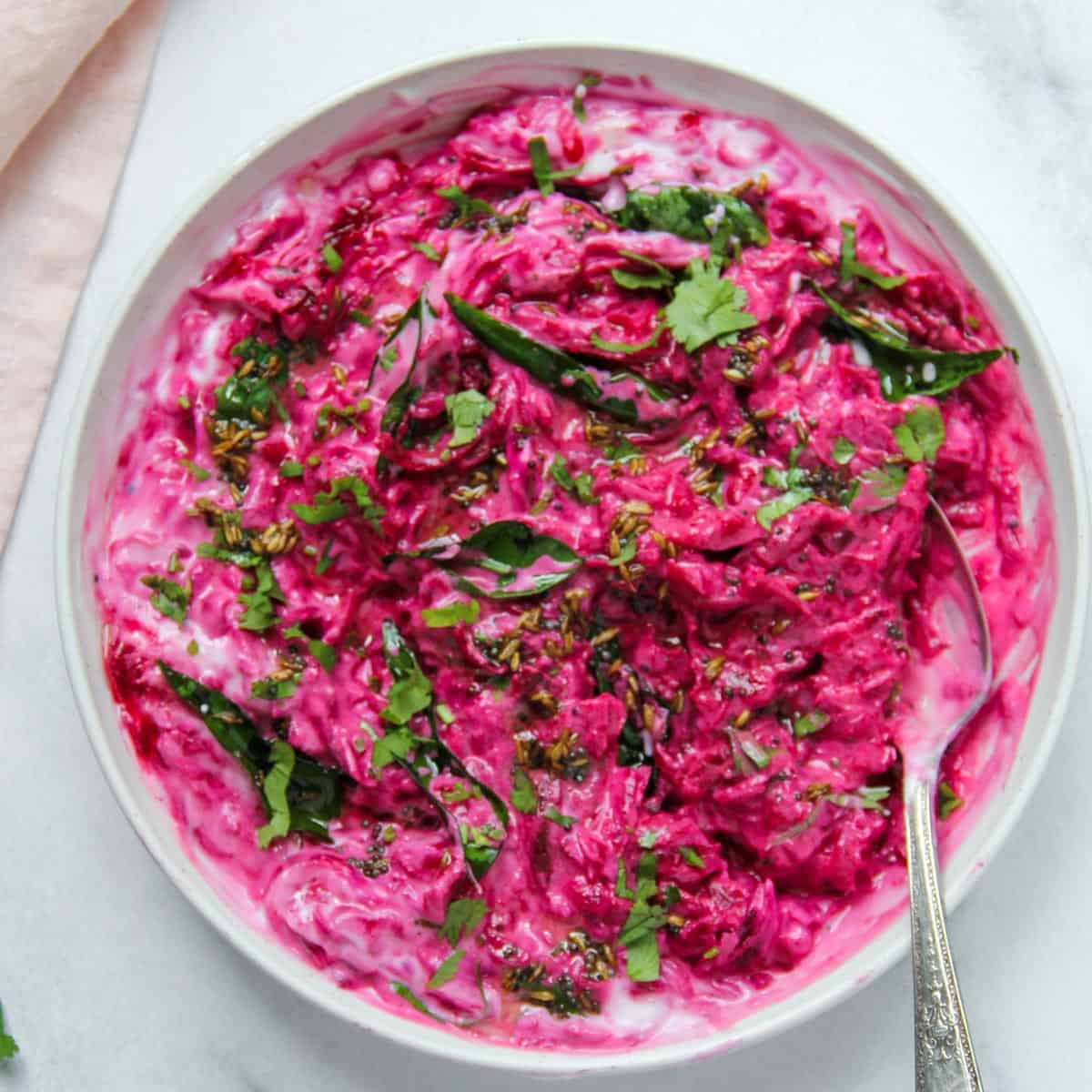 beet koshimbir in a white bowl garnished with cilantro and curry leaves