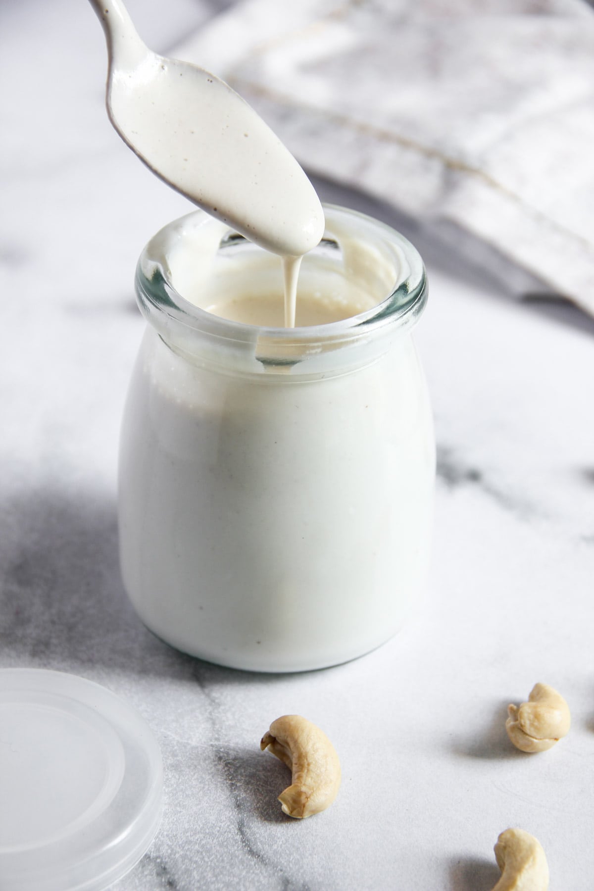 cashew cream dripping from a spoon into a glass bottle