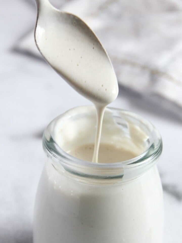 cashew cream dripping from a spoon into a glass bottle