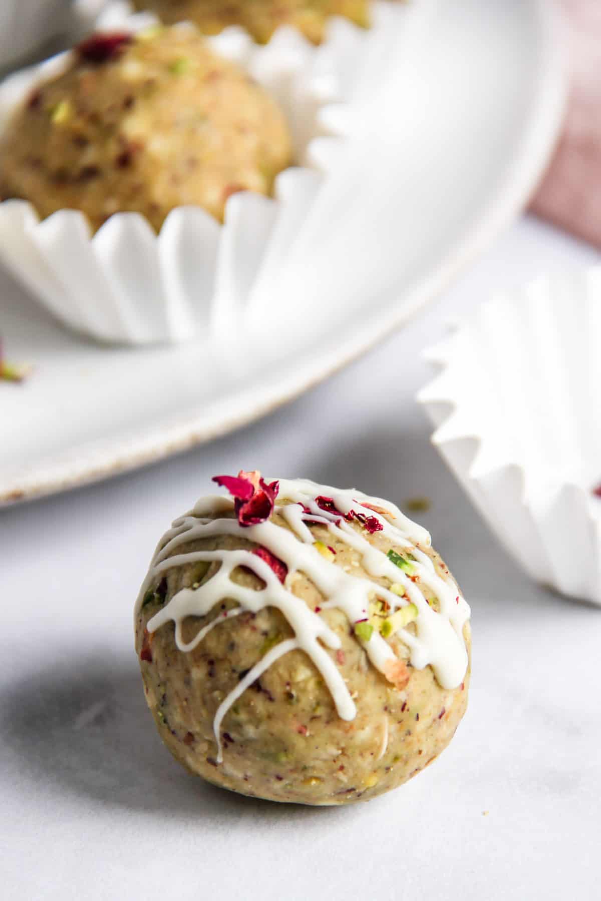 closeup photo of oats laddu with white chocolate drizzle on top 