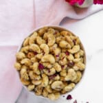 candied cashews in a bowl garnished with rose petals