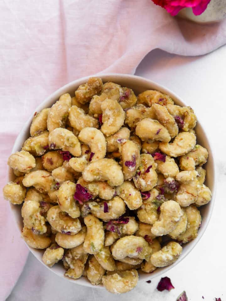 candied cashews in a bowl garnished with rose petals
