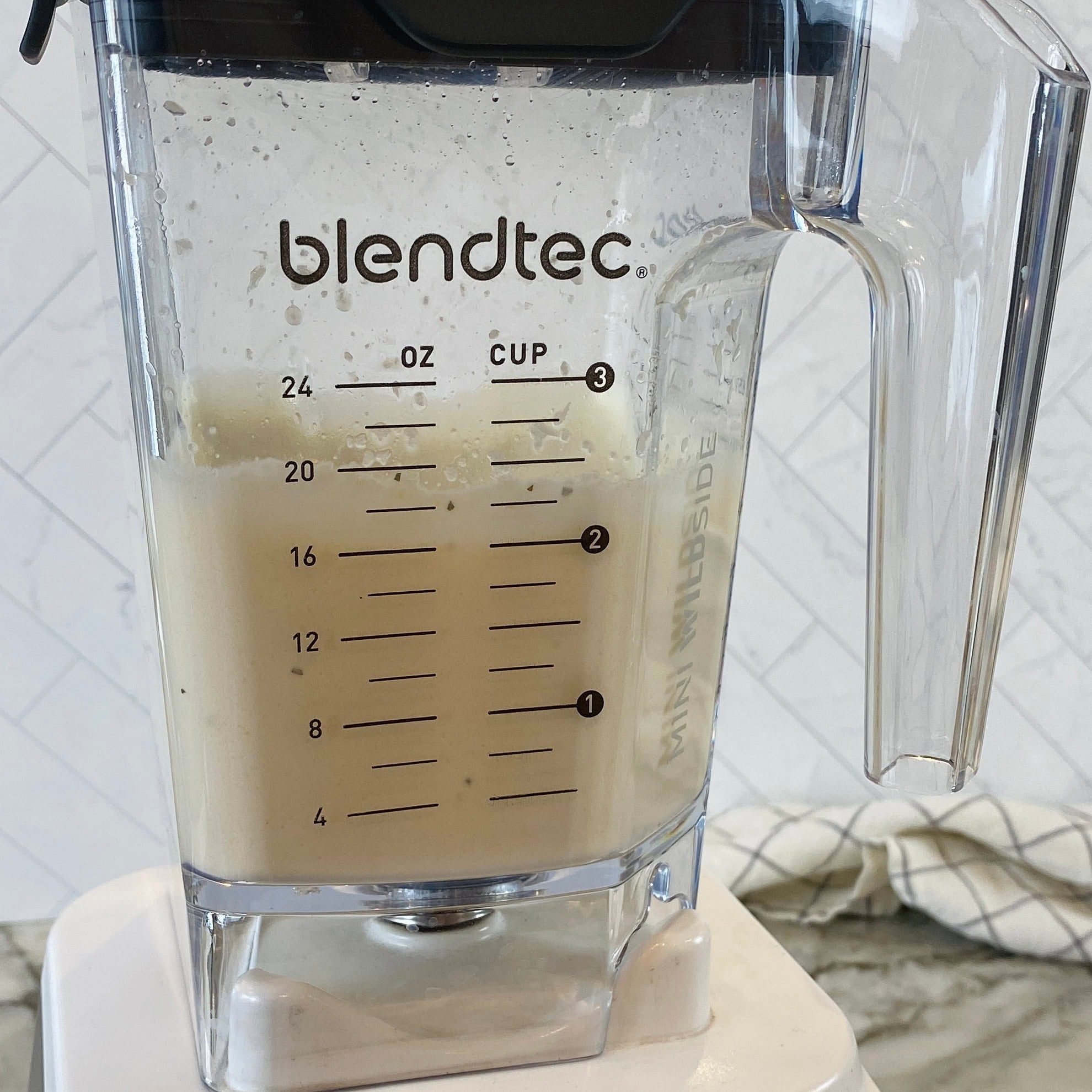 A Blendtec blender with creamy lentil batter, sitting on a white countertop.