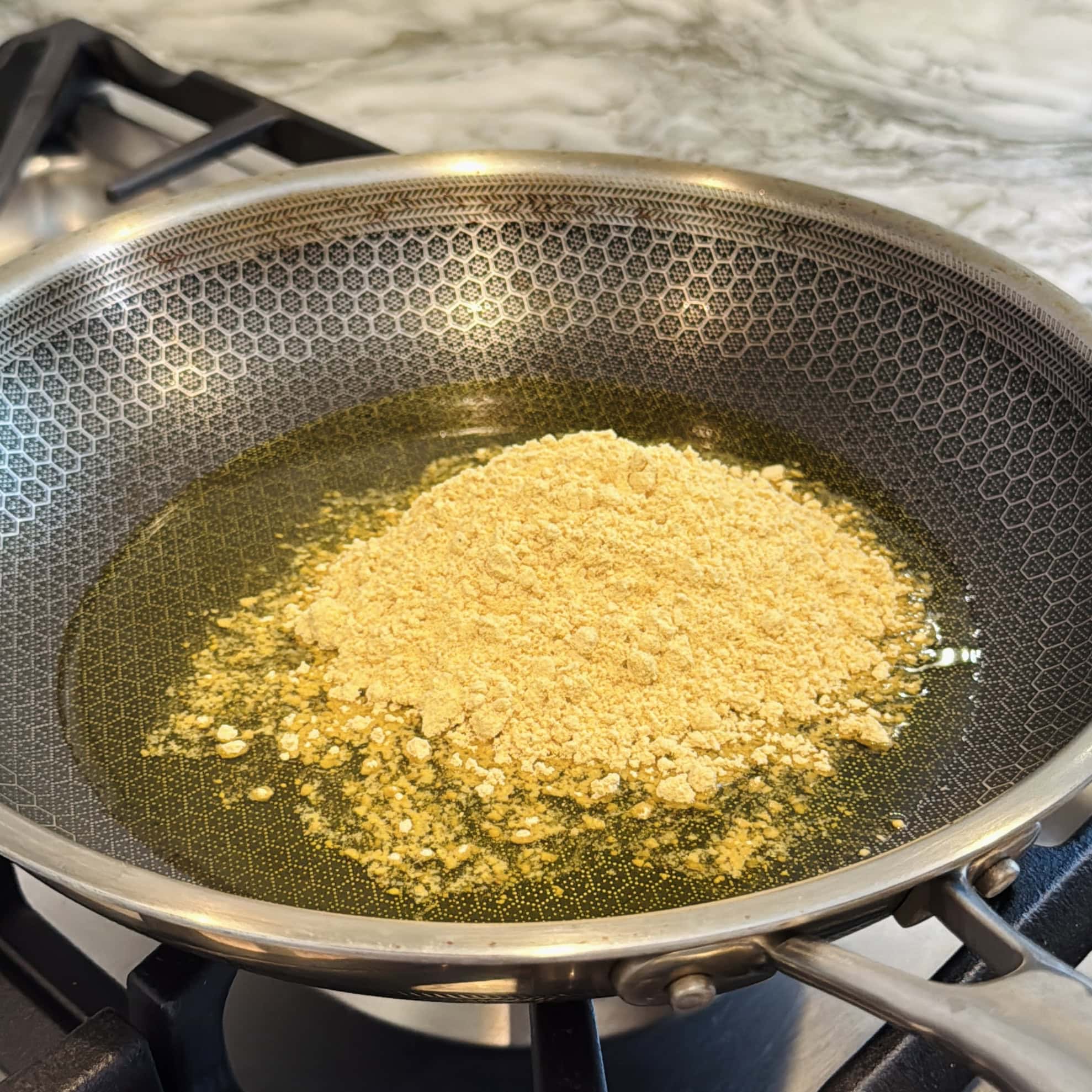 ghee and sattu atta in a non stick frying pan.