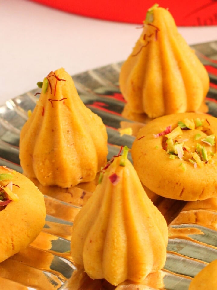 kisar malai modak and Peda garnished with saffron and pistachios.